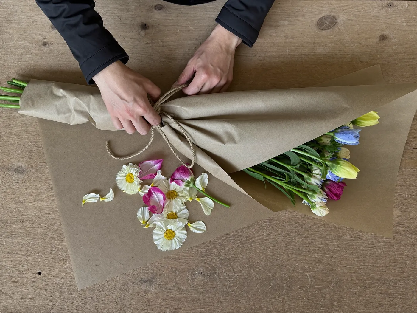 Mains qui emballent un bouquet dans du papier kraft