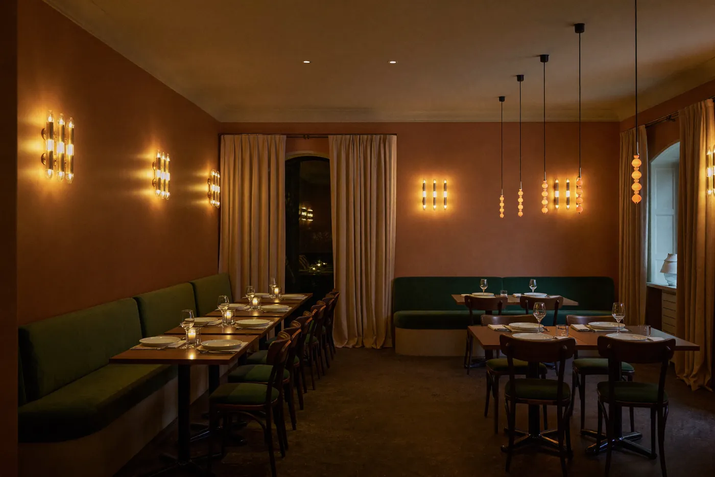 Salle de la trattoria le soir, murs terracotta et banquettes vertes